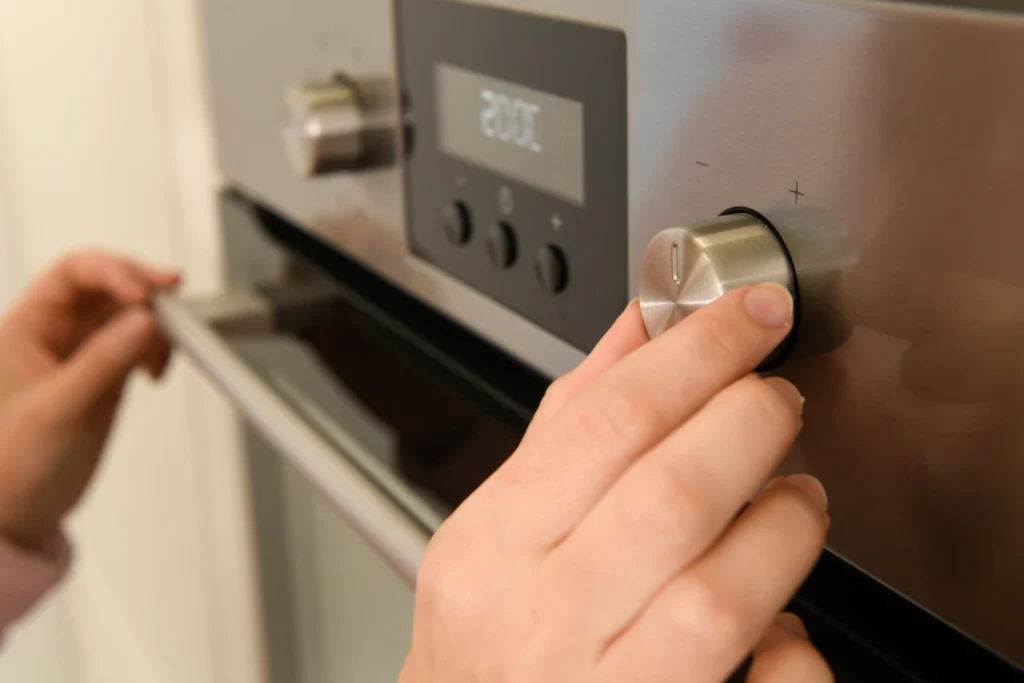 cuanto consume un horno electrico: mano regulando la temperatura de un horno
